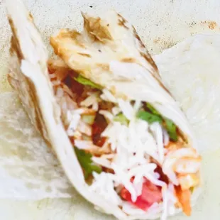 a tortilla with shredded cheese and vegetables