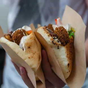 a person holding two tacos