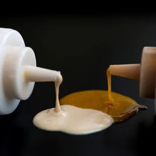 a bottle of ketchup being poured onto a piece of food