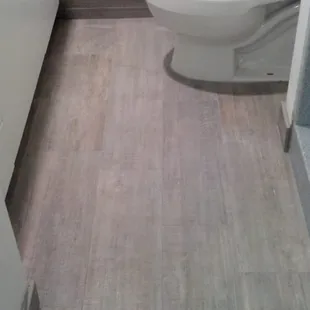 Ceramic tile that looks like wood. I chose the light gray for my guest bath. It also hides dirt &amp; dust really well.