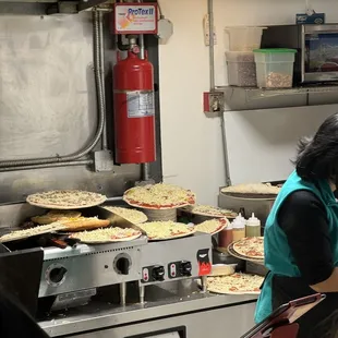 a woman making pizzas in a commercial kitchen
