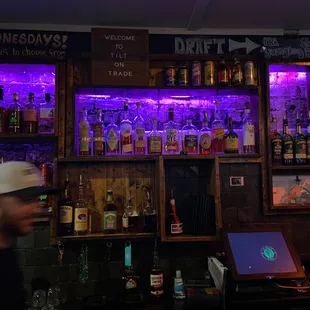 a man walking past a bar with purple lights