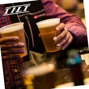 a man holding two cups of beer