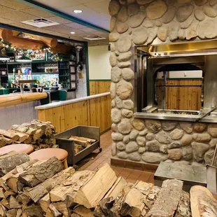wood stacked in front of a brick oven
