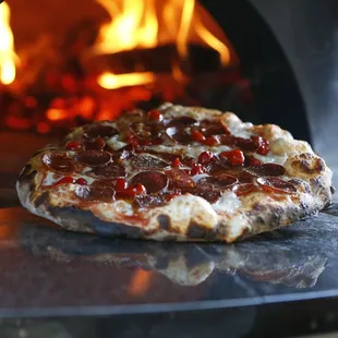 a pizza being cooked in a wood fired oven