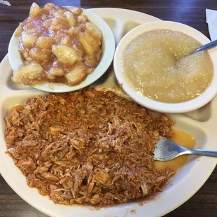 a plate of pulled pork, potatoes, gravy, and gravy soup