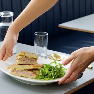 a person placing a sandwich on a plate