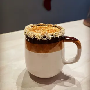 a cup of coffee with a cookie on top