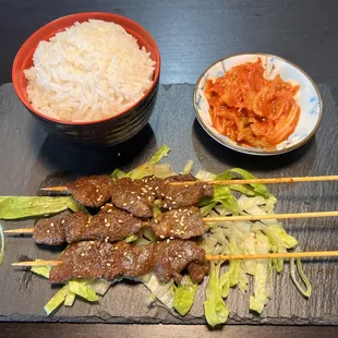 a bowl of rice and a plate of meat skewers