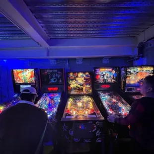 a row of pinball machines in a dark room