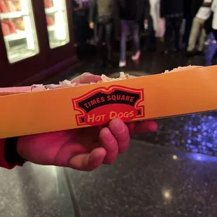 a hand holding a hot dog