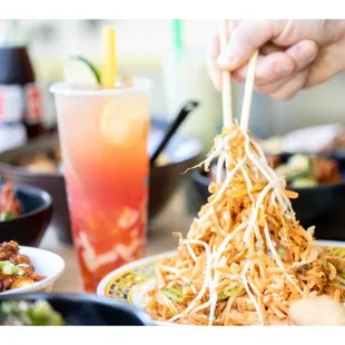 a person holding chopsticks over a plate of food