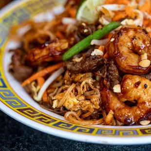 a bowl of stir fried noodles with shrimp, carrots,