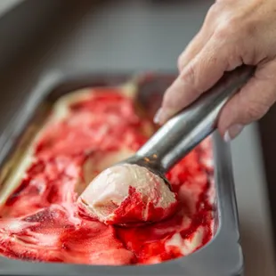 a person scooping a scoop of ice cream into a pan