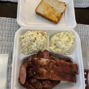 Tin Roof plate with sliced brisket, ribs, and sausage with coleslaw and potato salad