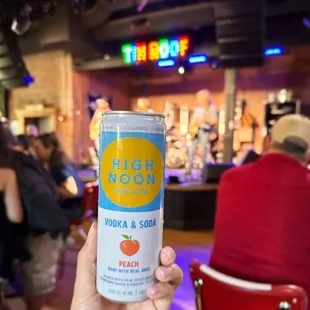a person holding a can of high noon