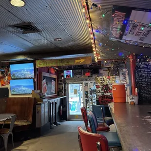 a bar with red chairs and a television