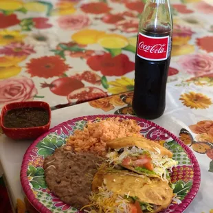 a plate of mexican food and a bottle of coke