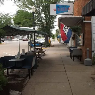 ows a sidewalk with tables and umbrellas