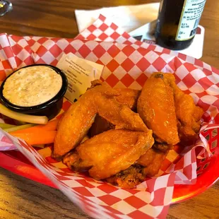 a basket of chicken wings with a side of ranch dip