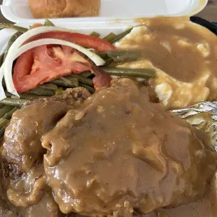 Smothered pork chops mashed potatoes and green beans.