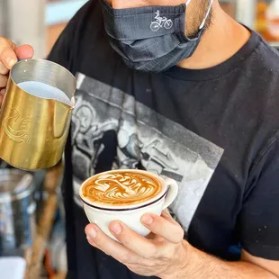 a man wearing a face mask and drinking a cup of coffee