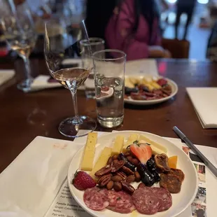a plate of meat and cheese with a glass of wine