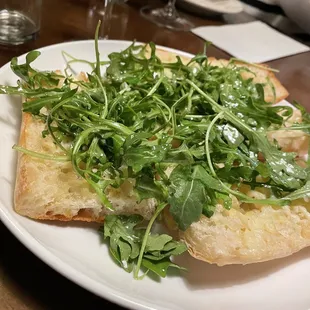 a plate of bread with arugula on it