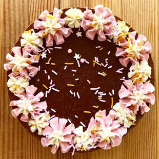 a chocolate cake with pink frosting and sprinkles