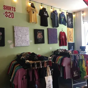 Many shirts, printed locally at Tanline Printing, featuring artwork from local artists
