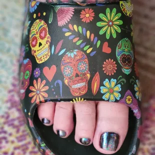 Pedicure with black gel polish and chameleon flake on top.