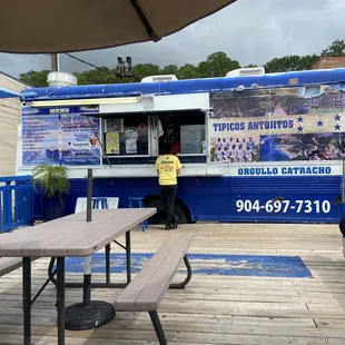 a woman sitting on a bench in front of a food truck