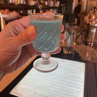 a hand holding a glass of cocktail