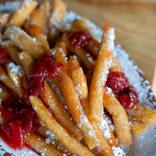 a plate of french fries with strawberries and powdered sugar