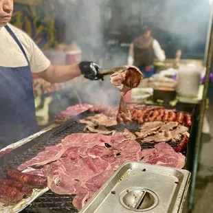 a man cooking meat on a grill