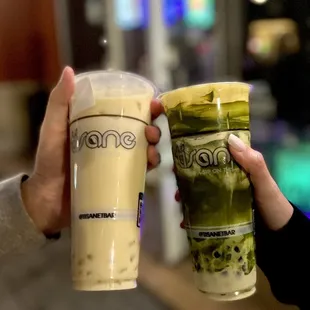 two people holding cups of iced coffee