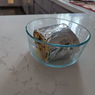 Breakfast burrito, so large that even half of it fills an entire glass lock container.