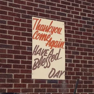 a thank you come again sign on a brick wall