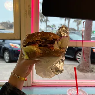 a person holding a sandwich in front of a window