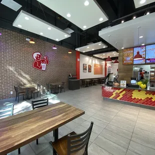 Interior shot of store with TKK logo on brick wall; tv monitors with menu items and promotional posters.