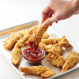 a person dipping ketchup on a tray