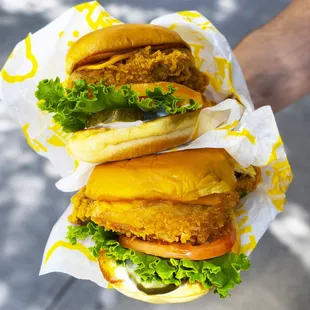 a hand holding three sandwiches