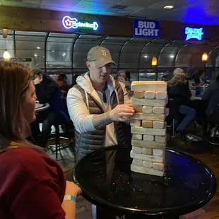 a man and a woman playing a game of giant blocks