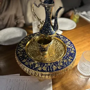 a blue and gold teapot on a brass plate