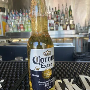 a bottle of corona beer sitting on a bar