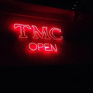 a neon sign that reads tmc open