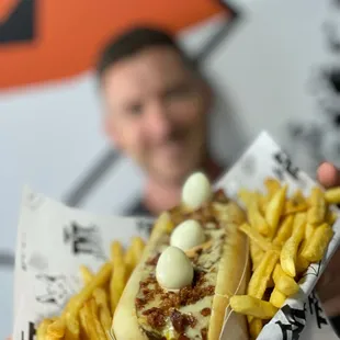 a man holding a hot dog and french fries