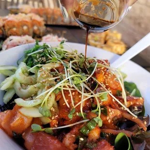 a person pouring sauce over a bowl of food
