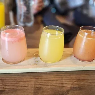 four glasses of fruit juice on a cutting board
