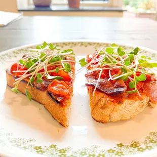 two slices of toast with tomatoes and sprouts